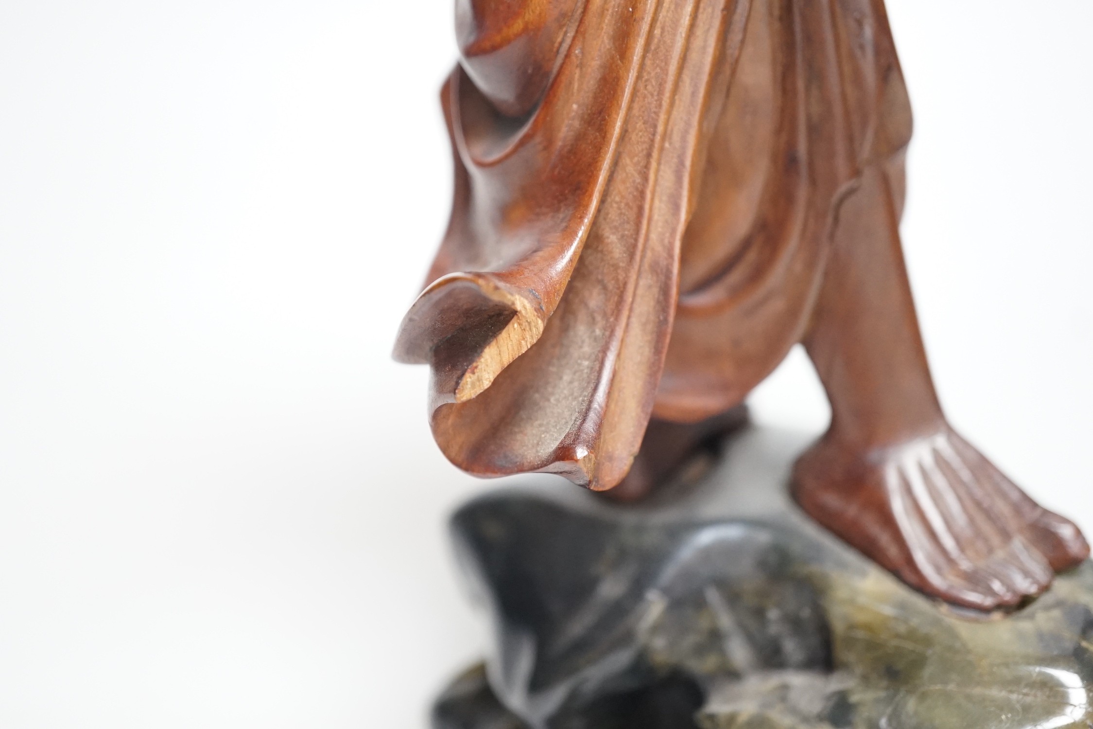 An early 20th century Chinese hardwood carving of a luohan, on soapstone base, 36cm tall